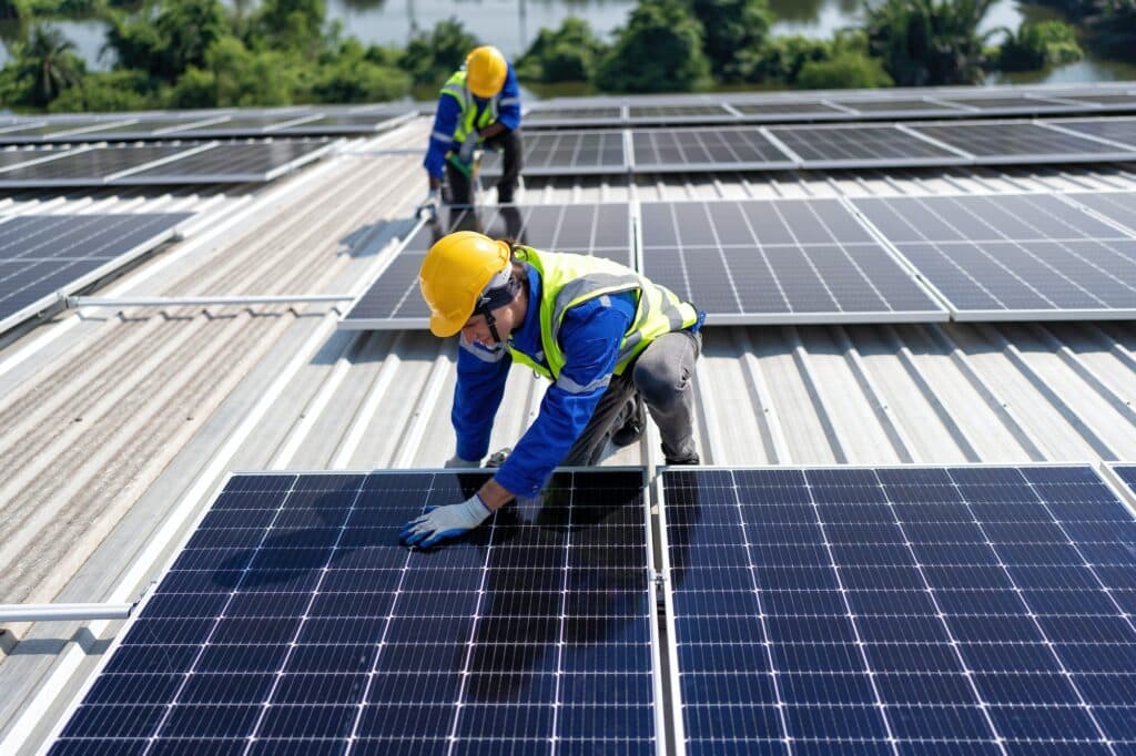 engineer-on-rooftop-kneeling-next-to-solar-panels-photo-voltaic-with-tool-in-hand-for-installation