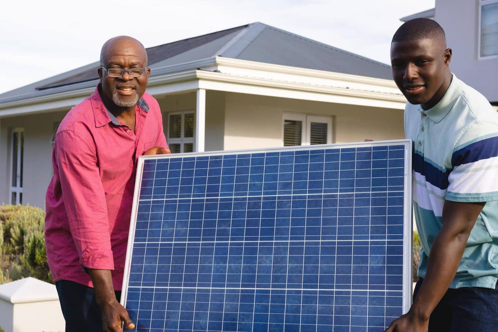 african american senior man with son carrying solar panel